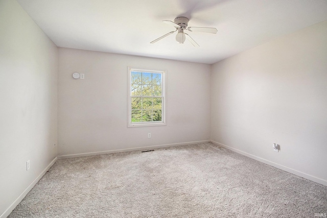 carpeted spare room with ceiling fan and baseboards