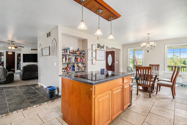 kitchen featuring black electric stovetop, light tile patterned floors, a center island, a chandelier, and a ceiling fan