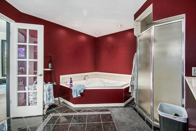 full bathroom with a shower stall, a jetted tub, tile patterned flooring, and baseboards