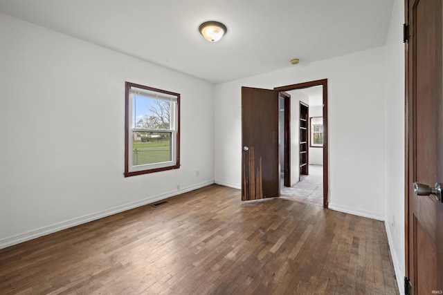 unfurnished room with healthy amount of natural light, wood-type flooring, and baseboards