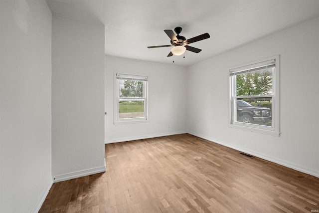 empty room with wood finished floors, a ceiling fan, and baseboards