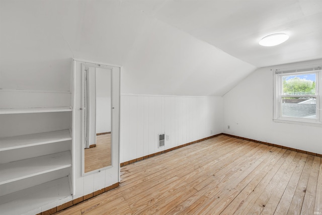 additional living space featuring hardwood / wood-style flooring, baseboards, and lofted ceiling