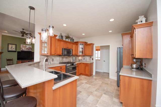 kitchen featuring stainless steel microwave, double oven range, freestanding refrigerator, a sink, and a peninsula