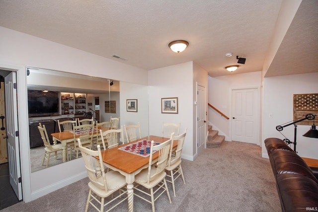 carpeted dining area featuring stairs, baseboards, bar, and a textured ceiling