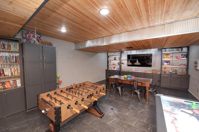 rec room with concrete block wall, dark marble finish floors, and wooden ceiling