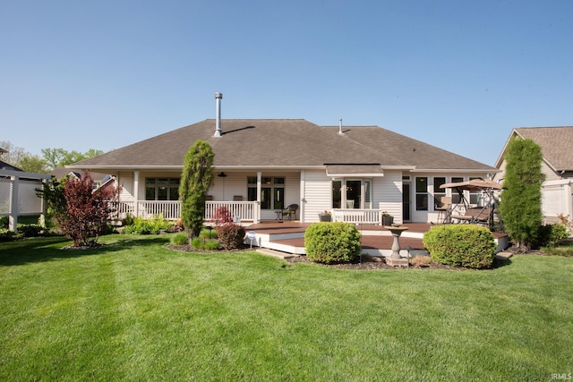 back of house featuring a yard and a shingled roof