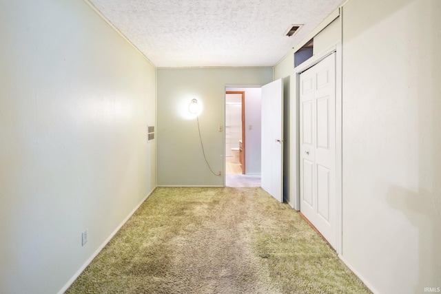 hallway with carpet floors, a textured ceiling, and baseboards