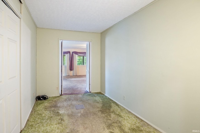 hallway featuring carpet floors, a textured ceiling, and baseboards