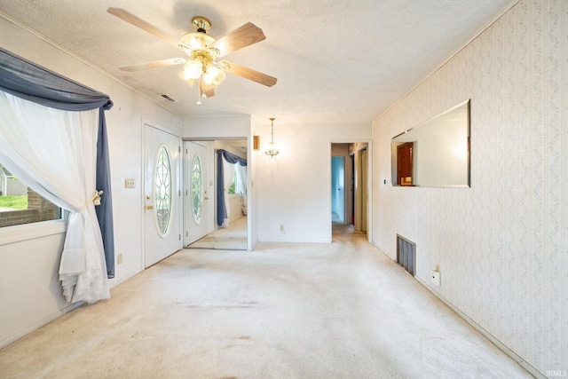 spare room featuring a ceiling fan, a textured ceiling, carpet flooring, wallpapered walls, and baseboards