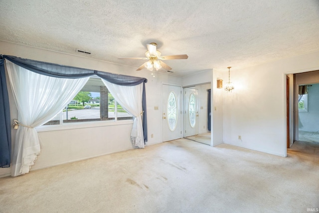 unfurnished bedroom with multiple windows, a textured ceiling, carpet, and a chandelier