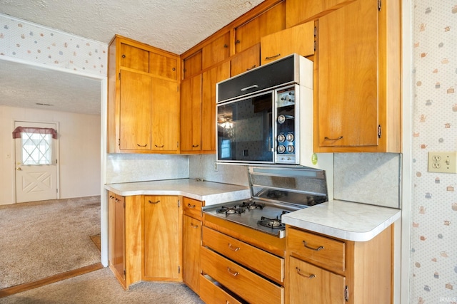 kitchen featuring wallpapered walls, light colored carpet, black microwave, light countertops, and a textured ceiling
