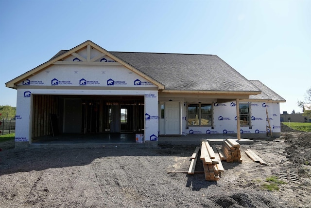 property in mid-construction featuring a garage, roof with shingles, and driveway