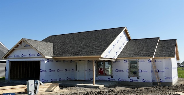 unfinished property with an attached garage and a shingled roof