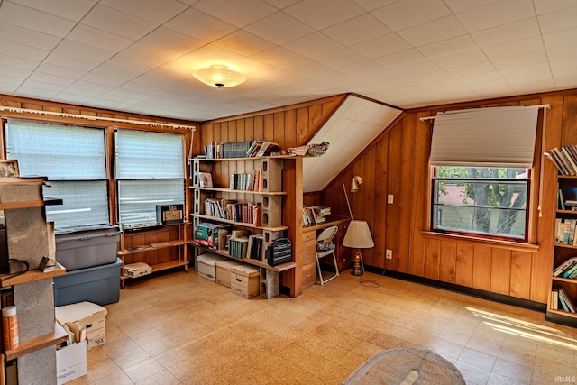 sitting room with wood walls, vaulted ceiling, and light flooring