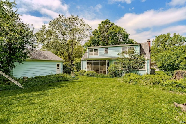 back of house featuring a sunroom, a chimney, a yard, and central air condition unit