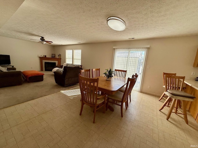 dining area featuring ceiling fan, brick patterned flooring, a fireplace, a textured ceiling, and baseboards