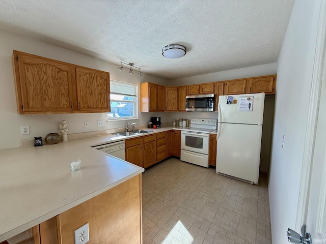 kitchen featuring white appliances, a sink, light countertops, brown cabinetry, and brick patterned floors