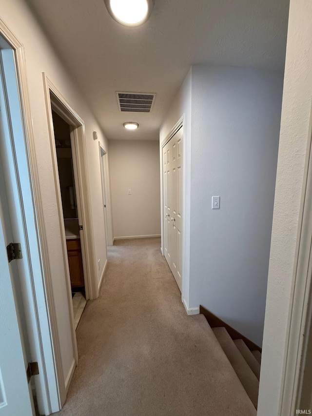 corridor featuring light colored carpet and baseboards