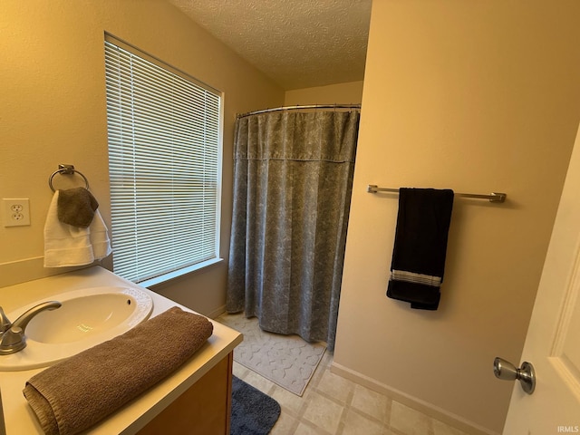 bathroom featuring a textured ceiling, curtained shower, vanity, and baseboards