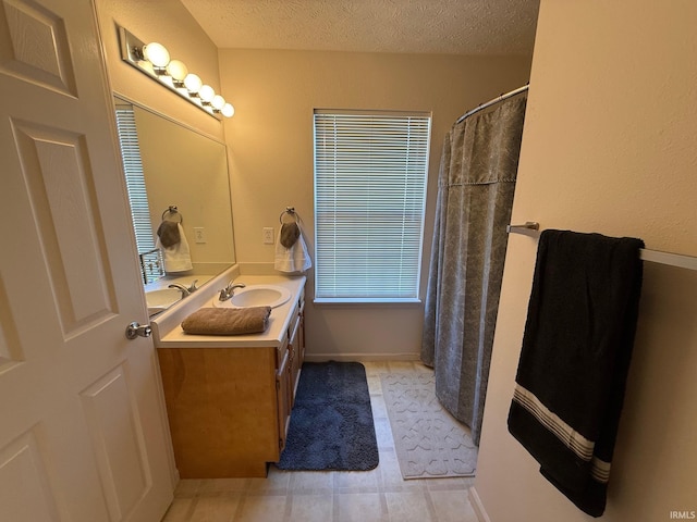 full bathroom featuring a textured ceiling, vanity, a shower with shower curtain, and baseboards