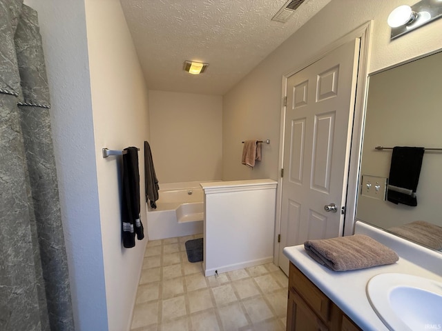 full bathroom featuring vanity, a garden tub, a textured ceiling, and tile patterned floors