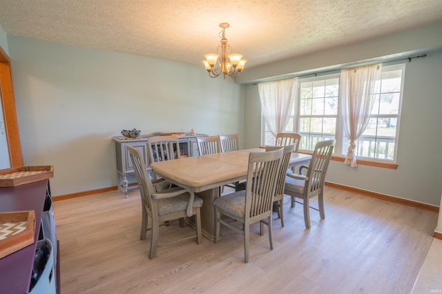 dining area featuring light wood finished floors, a chandelier, a textured ceiling, and baseboards