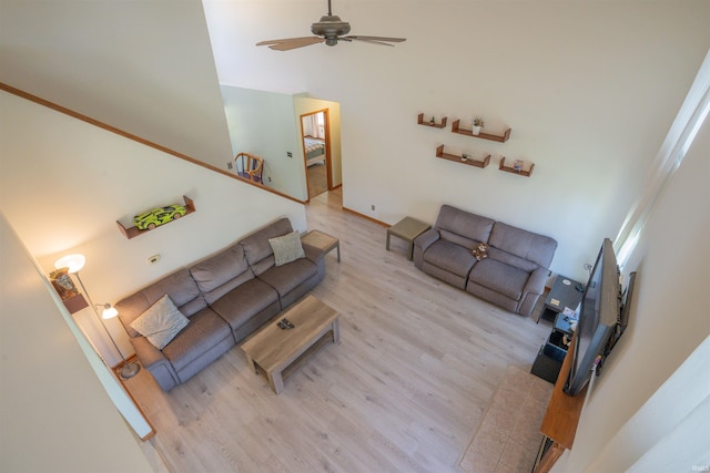 living area with wood finished floors, a ceiling fan, and a towering ceiling