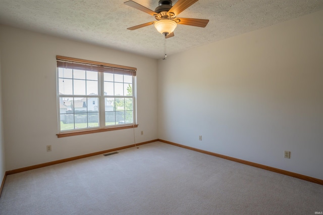 unfurnished room with light carpet, a textured ceiling, ceiling fan, and baseboards