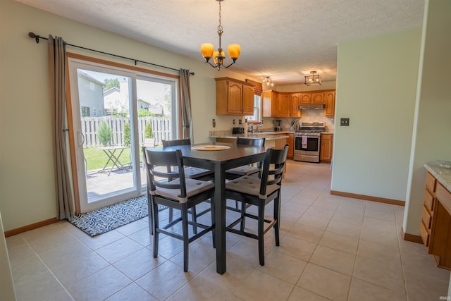 dining room featuring a chandelier, baseboards, a textured ceiling, and light tile patterned floors