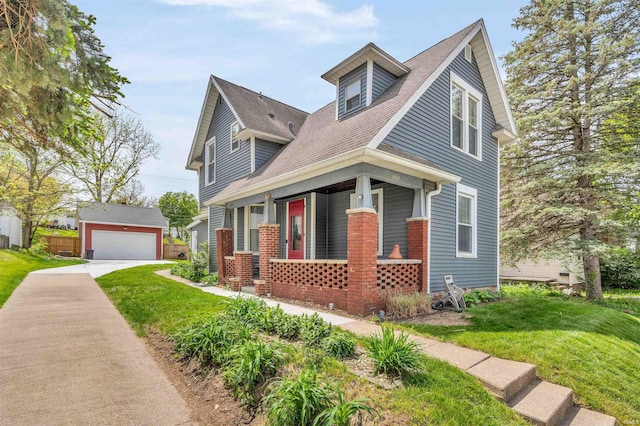view of front of property featuring a porch, an outbuilding, a front lawn, and a garage