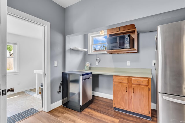 kitchen featuring freestanding refrigerator, black microwave, light countertops, baseboards, and refrigerator
