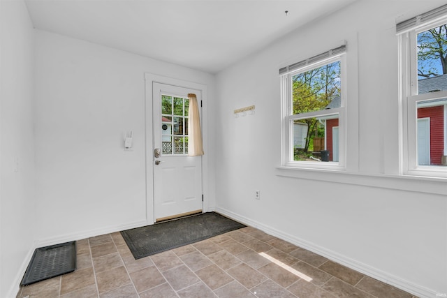 entrance foyer with healthy amount of natural light, baseboards, and stone finish floors
