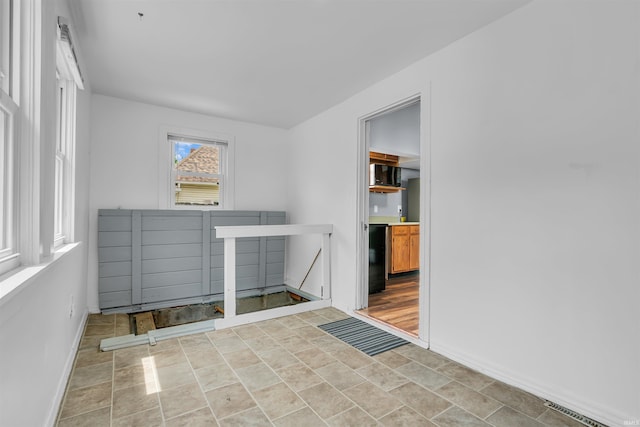 empty room with baseboards and stone finish floors