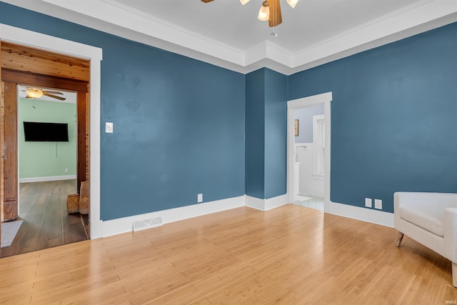 empty room featuring ceiling fan, wood finished floors, crown molding, and baseboards