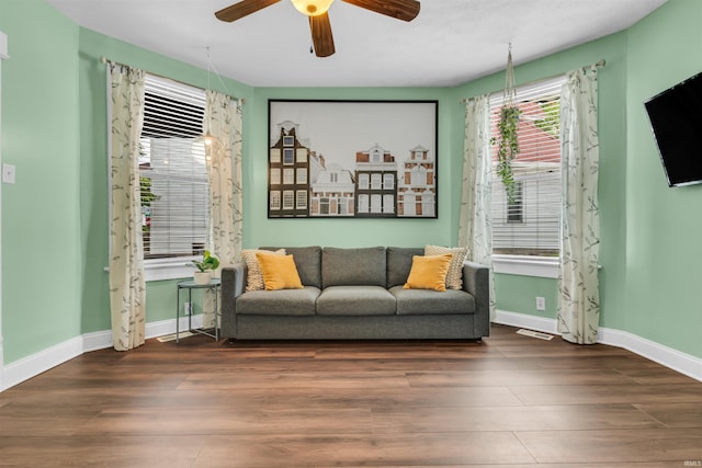 living area featuring wood finished floors, ceiling fan, and baseboards