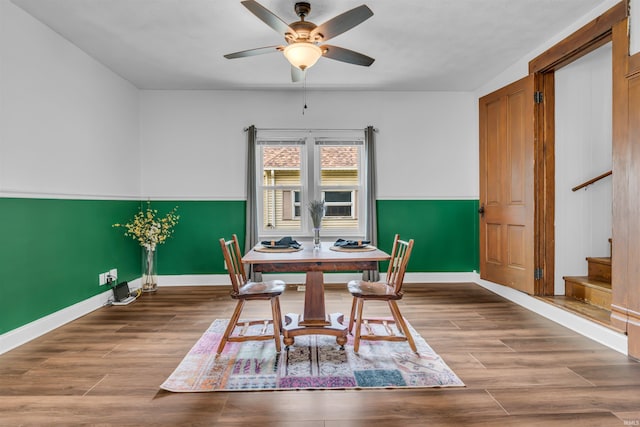 dining space with stairs, baseboards, ceiling fan, and wood finished floors