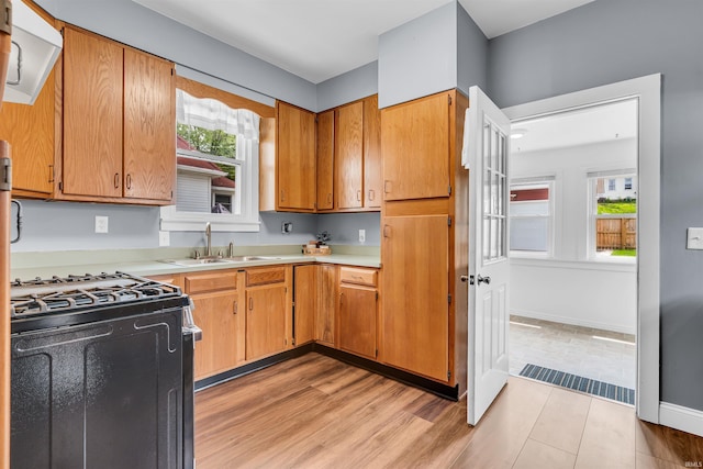 kitchen featuring gas stove, light countertops, a sink, and light wood-style floors