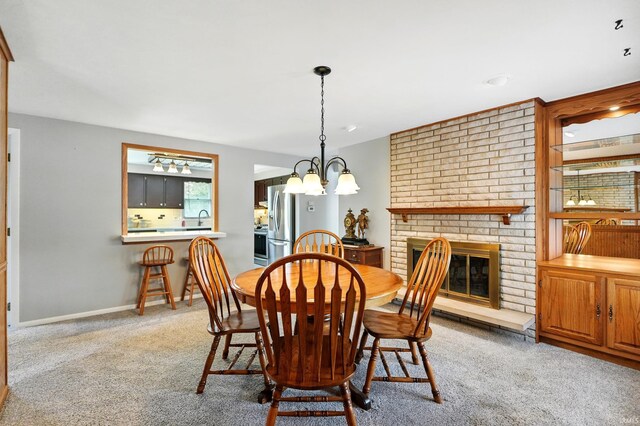dining area featuring carpet flooring, a brick fireplace, a chandelier, and baseboards
