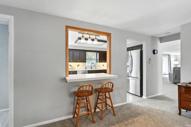 kitchen featuring stainless steel appliances, light carpet, and a sink