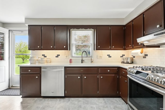 kitchen featuring appliances with stainless steel finishes, a sink, under cabinet range hood, and light countertops