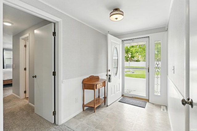 entrance foyer featuring wainscoting and ornamental molding
