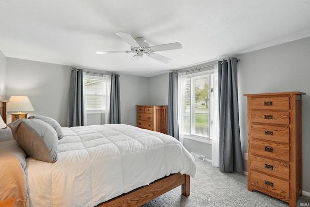 bedroom featuring light carpet, multiple windows, ceiling fan, and baseboards