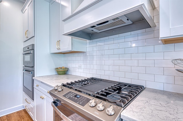 6055 Logel Rd, Newburgh, IN 47630 - kitchen featuring premium range hood, appliances with stainless steel finishes, decorative backsplash, light stone counters, and white cabinetry