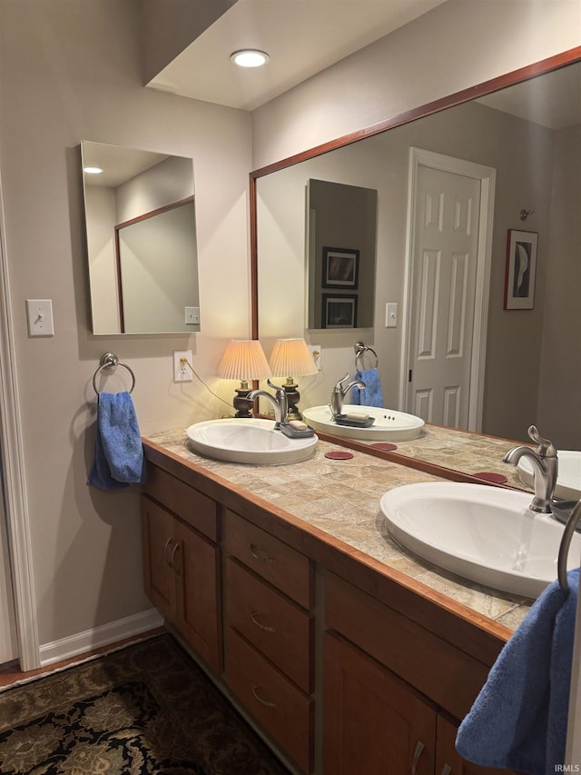 full bath featuring double vanity and baseboards