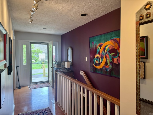 foyer entrance featuring wood finished floors, track lighting, and a textured ceiling