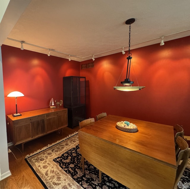 dining space with track lighting and wood finished floors
