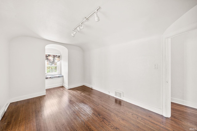 1602 Cedar St, South Bend, IN 46617 - empty room with track lighting, lofted ceiling, wood-type flooring, baseboards, and arched walkways