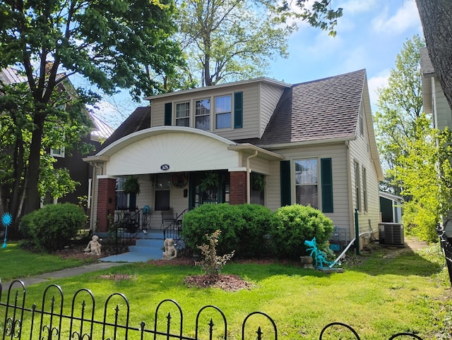 view of front of house featuring covered porch, a front lawn, roof with shingles, brick siding, and central AC unit