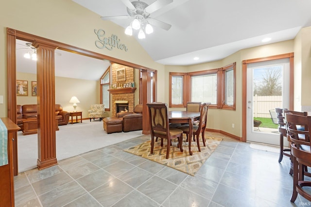 dining space with lofted ceiling, decorative columns, ceiling fan, a fireplace, and baseboards