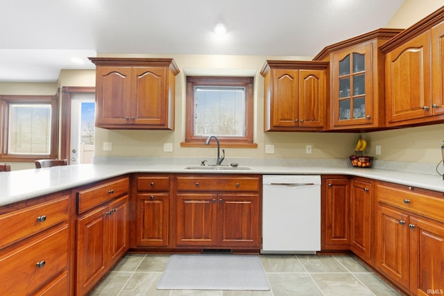 kitchen featuring white dishwasher, a sink, light countertops, and glass insert cabinets